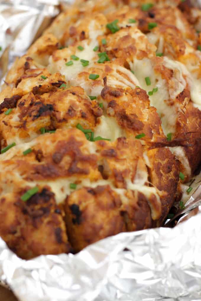 Cheesy Pesto Garlic Pull Apart Bread - A cheese filled treat. The perfect side dish for dinner or snacking. Pesto adds a depth of flavour to this pull apart bread with the mountains of melting mozzarella cheese.