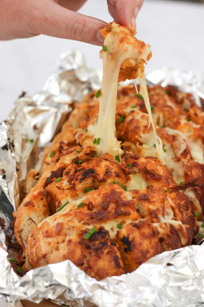 Cheesy Pesto Garlic Pull Apart Bread - A cheese filled treat. The perfect side dish for dinner or snacking. Pesto adds a depth of flavour to this pull apart bread with the mountains of melting mozzarella cheese.