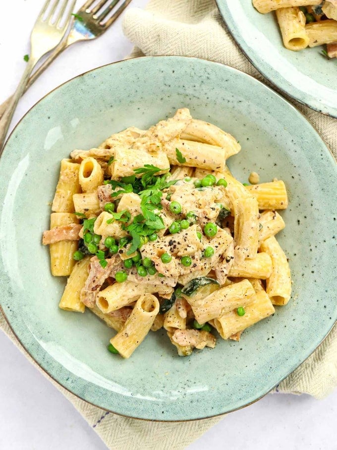 Quick and simple cream cheese pasta, cooked and on a green plate, with forks to the side.