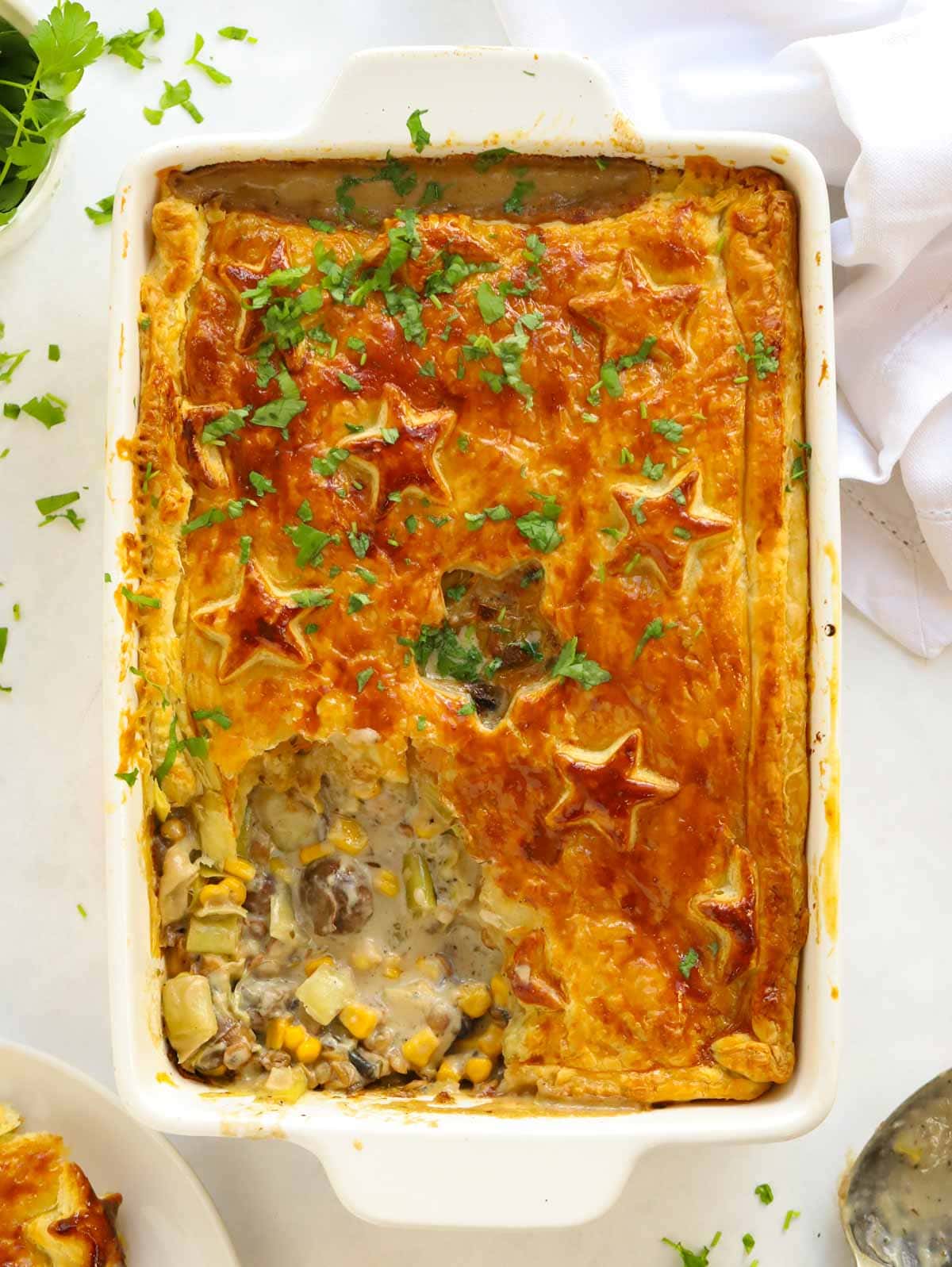 A pastry-crusted vegetarian pie out of the oven with piece missing.