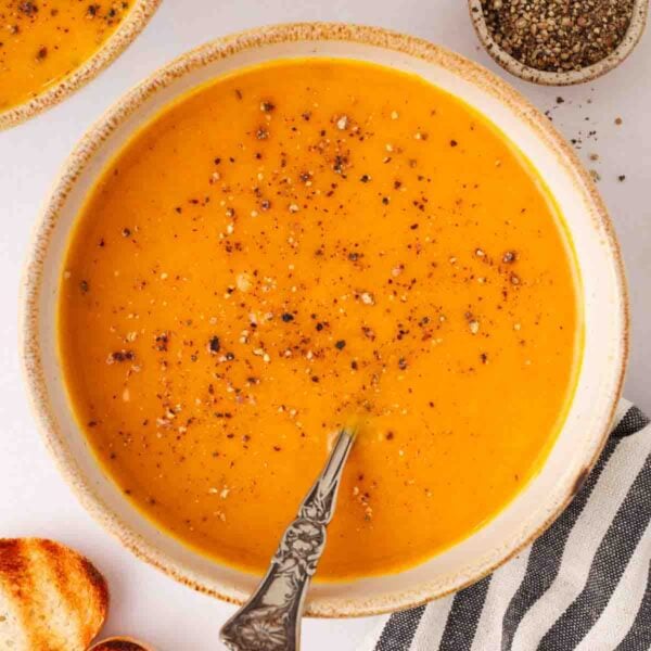 A bowl of orange soup with a spoon.