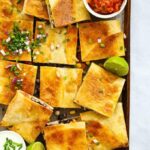 Sheet pan quesadillas cut into squares with lime and salsa.