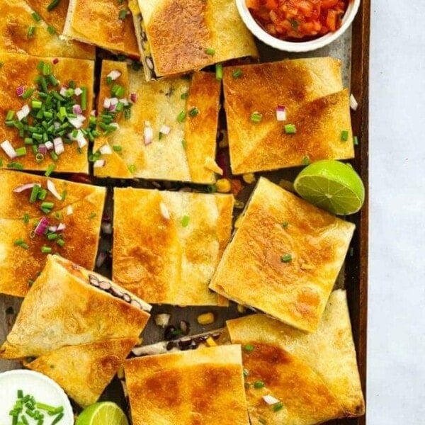 Sheet pan quesadillas cut into squares with lime and salsa.