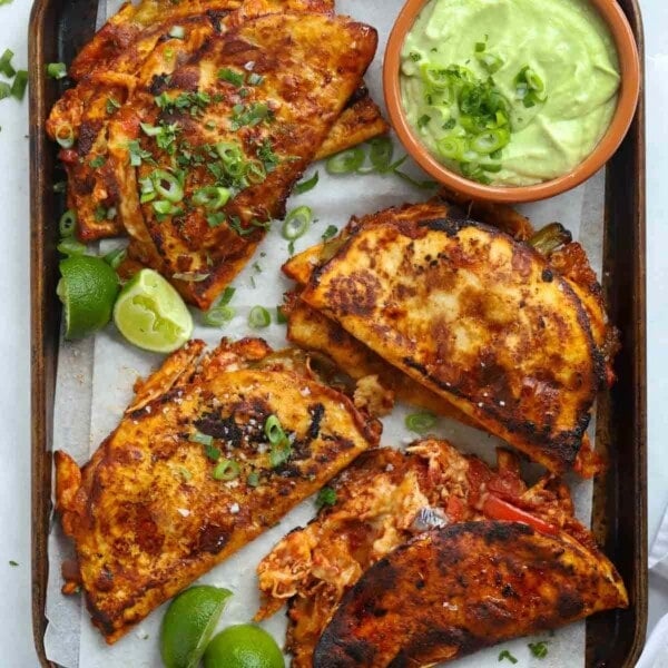 Fried tacos with tomato sauce and pulled chicken, melted cheese and an avocado dip on the side.