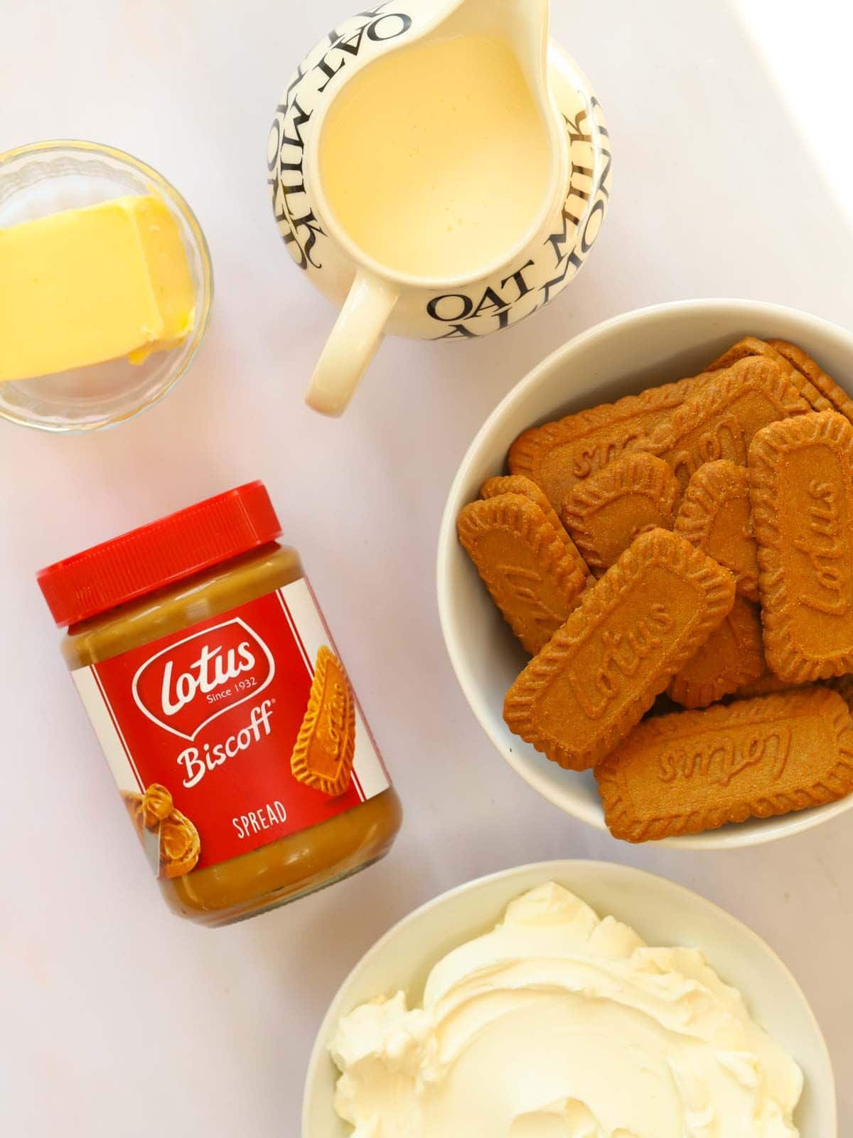 Ingredients laid out on a counter top. Butter, cream, biscuits, Biscoff butter and cream cheese.