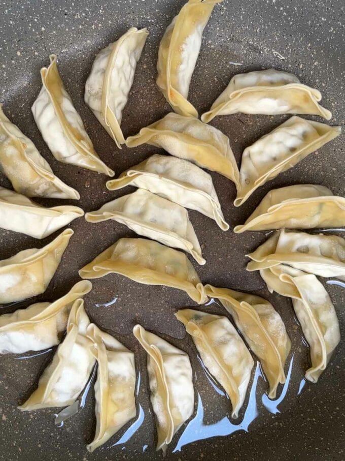 Gyoza dumplings in a pan for step 1 in the recipe for Gyoza Soup.