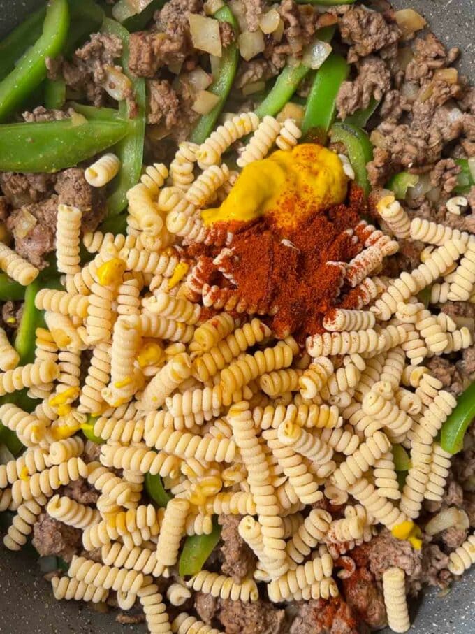 Mince, peppers and pasta cooking in a pan.