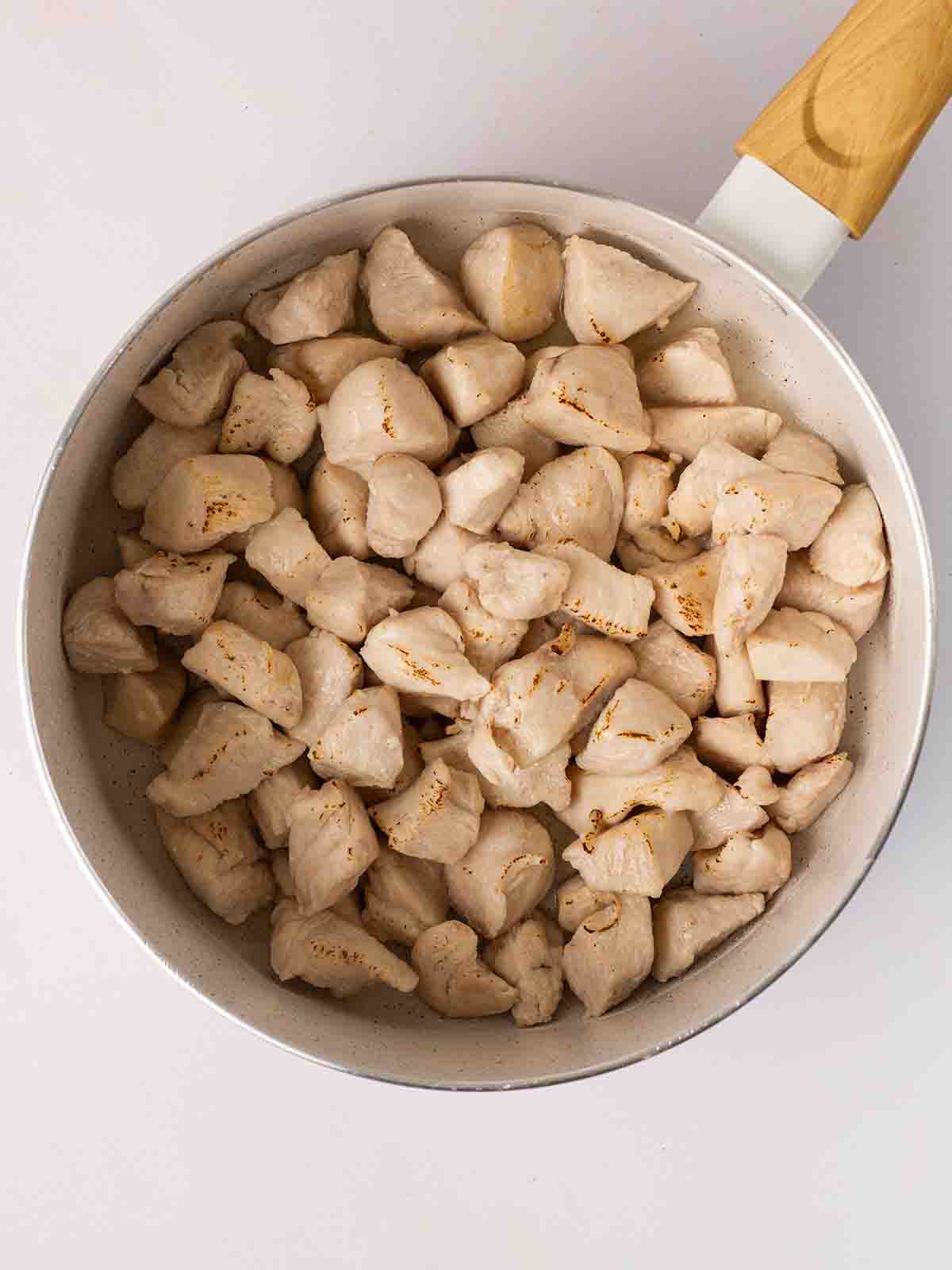 A pan filled with chunks of cooked chicken for step 1 in the recipe for Marry Me Chicken.