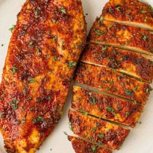 Two chicken breasts with coating on a white surface after being cooked in the air fryer.
