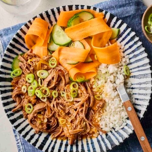 A close look at a placemat with a beef dish and rice and vegetables on a plate.