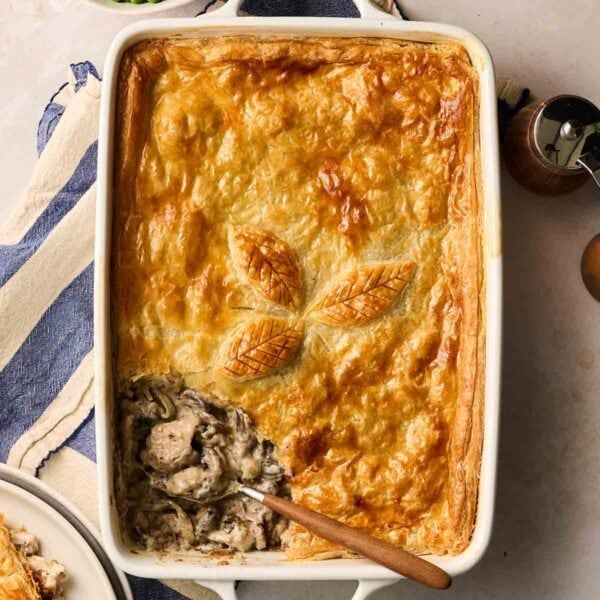 A pie with chicken and mushroom filing on a table, being served with a spoon.