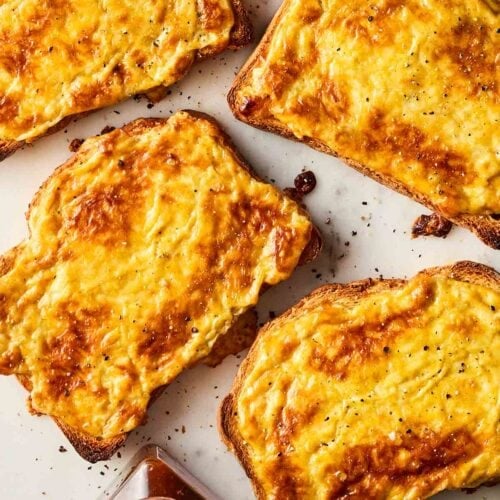 Fource slices of traditional Welsh rarebit ready to eat, with chutney to the side.