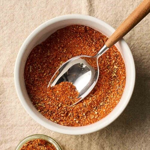 A bowl of spice mix and a smaller jar to the side.