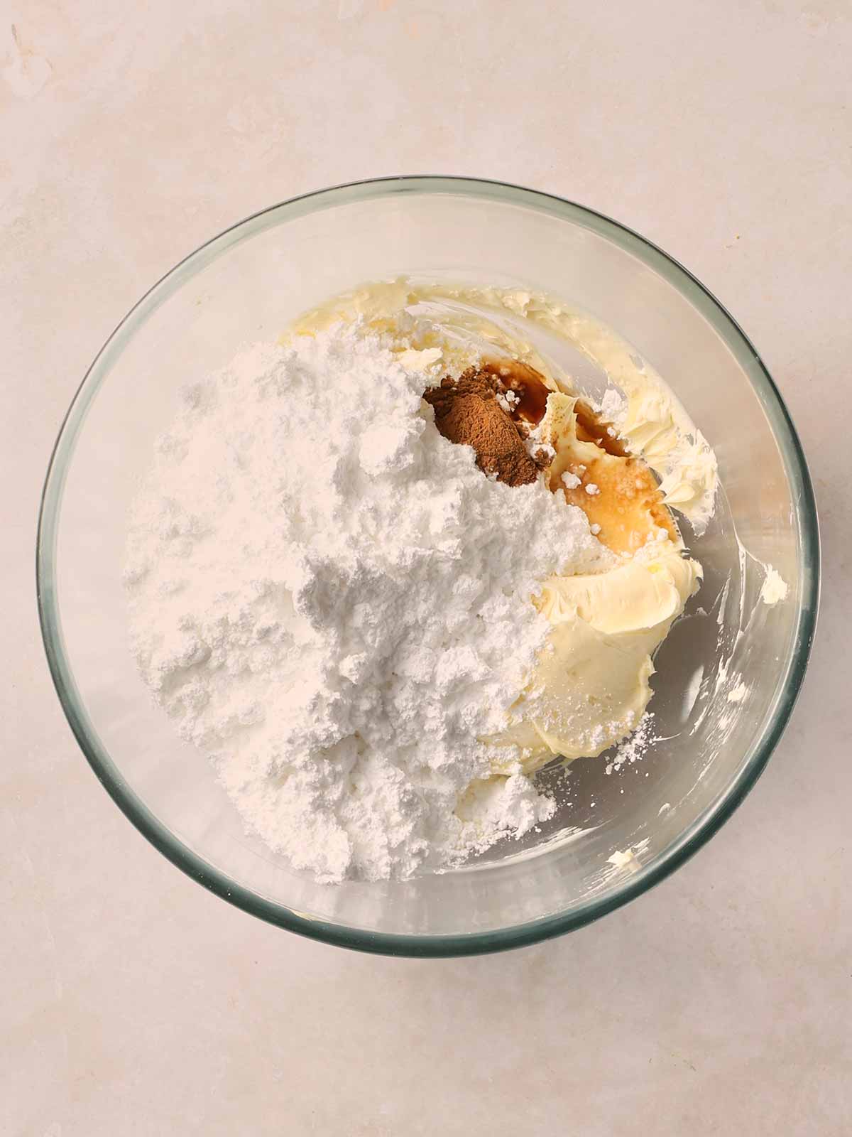 A glass bowl on a white surface filled with cupcake batter ingredients needing to be fully mixed.