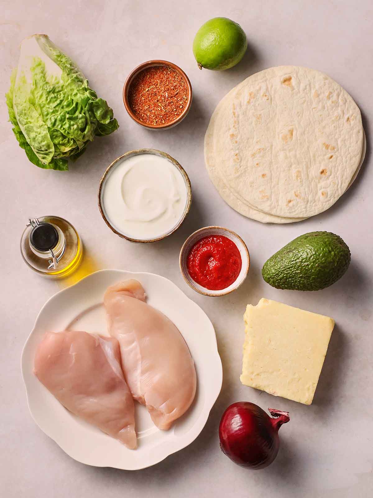 The raw ingredients for making Chicken Tacos laid out on a white table.