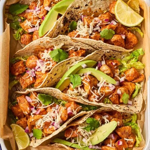 An oven tray with chicken tacos inside.