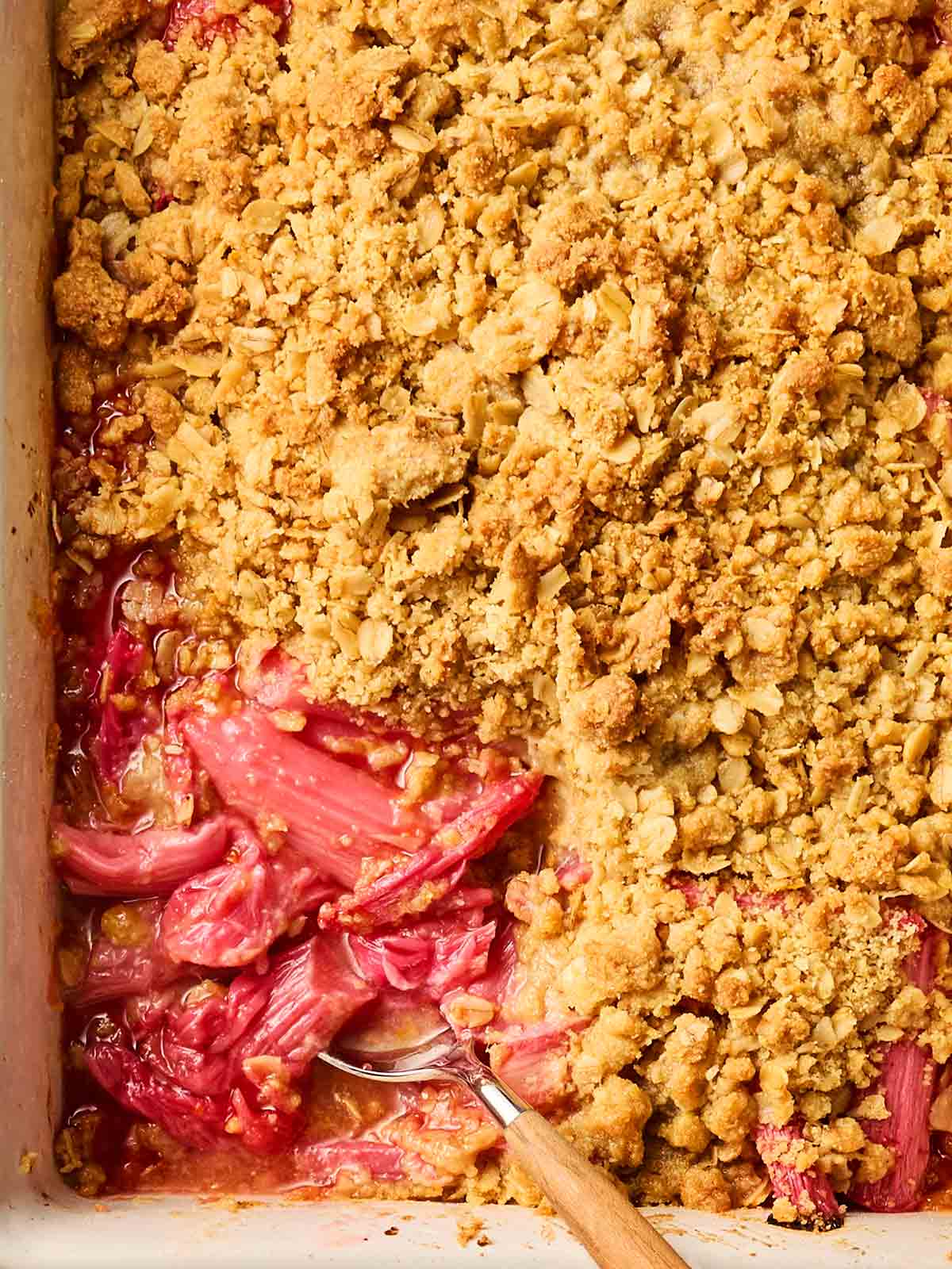 A classic rhubarb crisp close up, with pink filling and golden, crunchy topping.