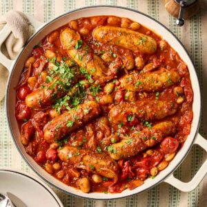 A large pot of sausage casserole with sausages and beans in a tomatoey sauce.