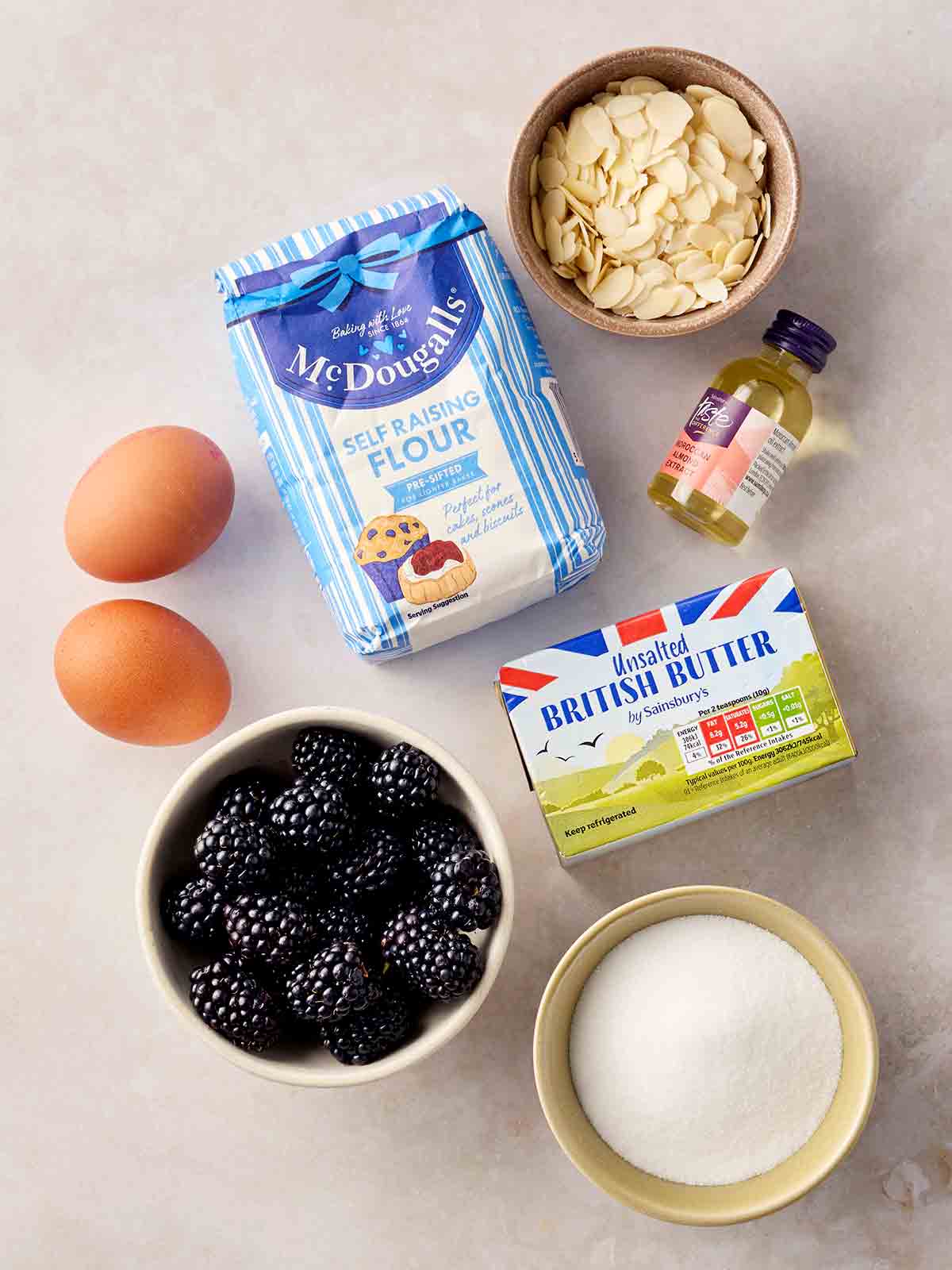 The ingredients for making blackberry cake laid out on a white counter.